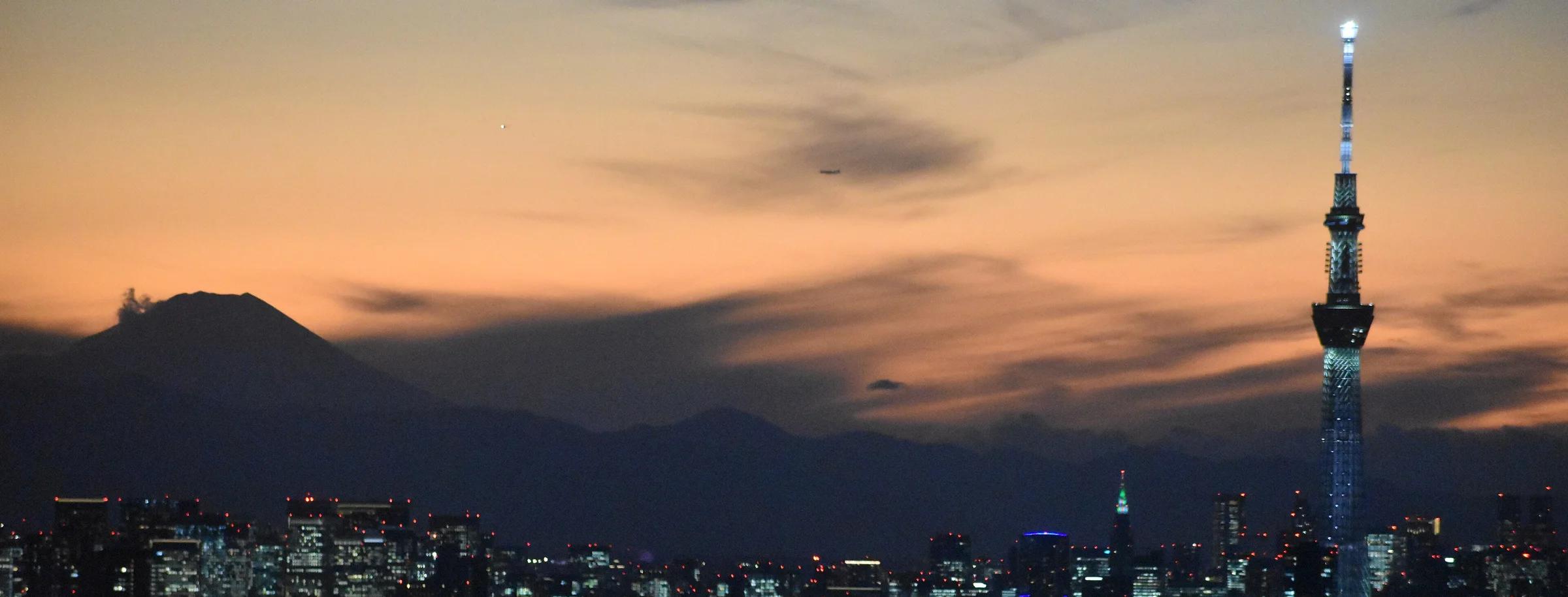 Tokyo Skytree, подсвеченная над вечерним городским горизонтом, с горой Фудзи на фоне